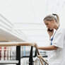 Bildet viser en kvinnelig sykepleier som snakker i telefonen mens hun holder fast i et gelebder