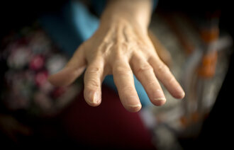 Bildet viser en eldre kvinnes hånd som strekker seg ut etter noe eller noen