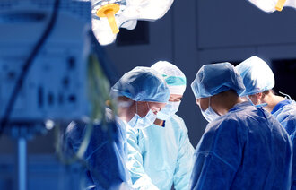 Bildet viser fire helsepersonell i ferd med å operere på en pasient