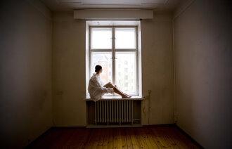 Bildet viser en kvinne som sitter alene i et vindu.