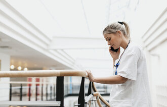 Bildet viser en kvinnelig sykepleier som snakker i telefonen mens hun holder fast i et gelebder