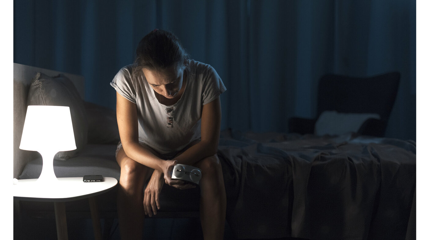 Søvnplager Bildet viser en kvinne som sitter på sengekanten og ikke får sove