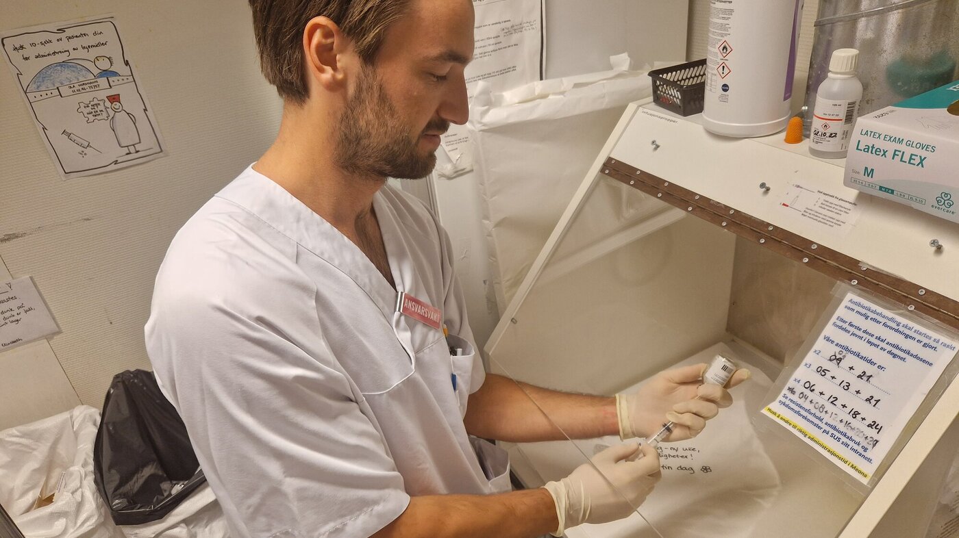 En mannlig sykepleier klargjør en sprøyte med antibiotika.