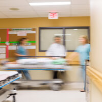 Bildet viser helsepersonell som triller en pasient i korridoren på et sykehus