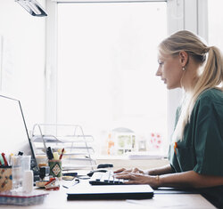Bildet viser en ung kvinnelige sykepleier som jobber foran en datamaskin
